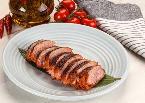 Tranches de magret de canard poêlé à la peau dorée disposées sur une feuille bambou, élaboré par un Producteur Foie Gras Artisanal.