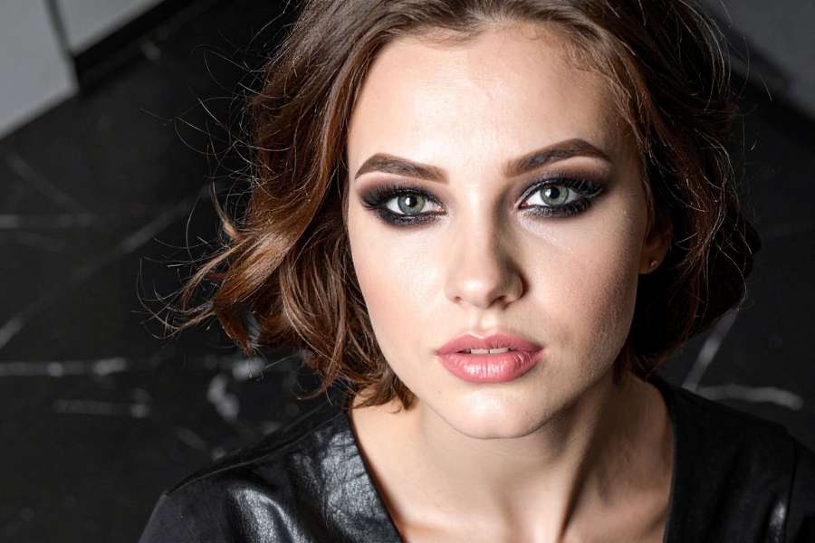 Un portrait en gros plan d'une femme aux yeux charbonneux intenses, illustrant comment réussir un smoky eye noir.